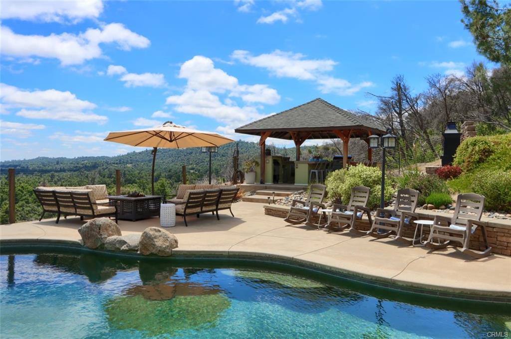 Poolside outdoor living space with covered gazebo, mountain views, and rolling hills in Mariposa County